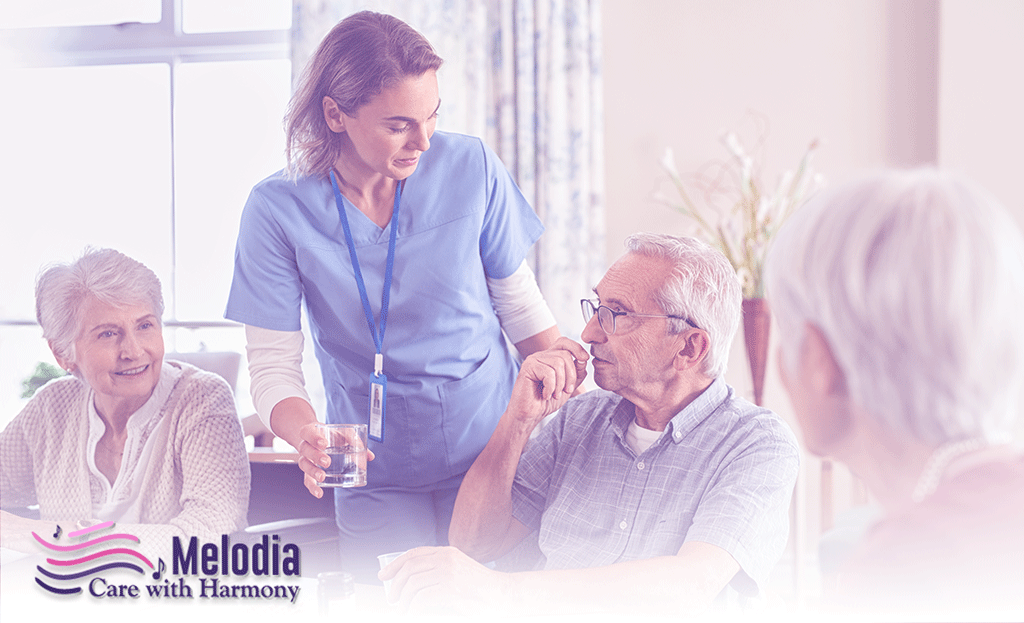 Hospice caregiver providing water to elderly person, surrounded by two elderly women